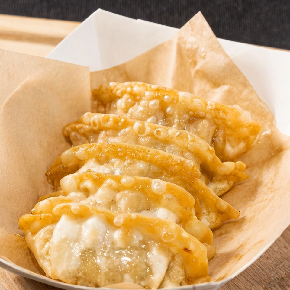 Golden fried dumplings arranged in a paper-lined serving tray on a wooden board.